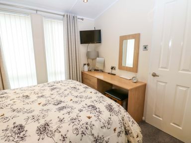 A bedroom with a bed, television, and desk at Plot 32 High Hesket near Armathwaite