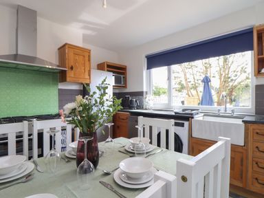 A kitchen with a dining table set with plates and glasses a green backsplash and wooden cabinets at The Heights in Truro