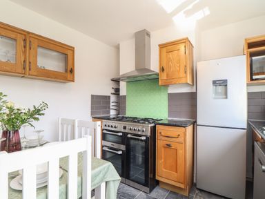 A kitchen with a dining table set with plates and flowers stove wooden cabinets and a refrigerator at The Heights in Truro