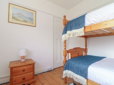 A bedroom with wooden bunk beds a wooden nightstand with a lamp and a framed painting on the wall at The Heights in Truro