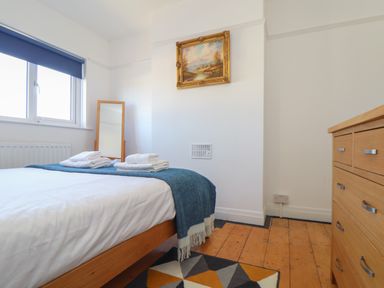 A bedroom with a bed with folded towels a wooden dresser a standing mirror and a painting on the wall at The Heights in Truro