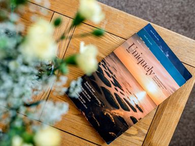 A wooden table with a magazine and blurred flowers in the foreground at Coot in Wheatacre