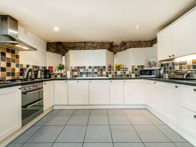 A kitchen with white cabinets a tiled backsplash a stove a microwave and a toaster at Coot in Wheatacre
