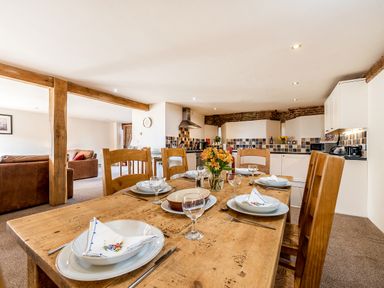 A dining table set with plates glasses and napkins in a kitchen and living area at Coot in Wheatacre