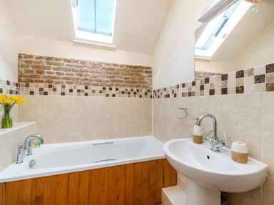 A bathroom with a bathtub wooden panel and a sink under skylight windows at Widgeon in Wheatacre