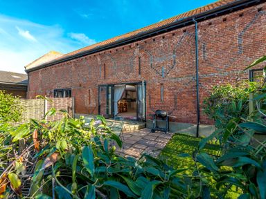 A backyard with patio furniture and a barbecue outside a brick building at Widgeon in Wheatacre