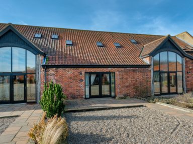 A building with a tiled roof brick walls multiple skylights and large glass doors at Widgeon in Wheatacre