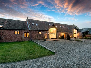 A brick house with large windows and a gravel driveway and lawn at Teal in Wheatacre