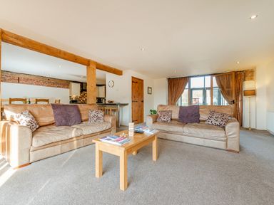A living room with two sofas, cushions, a wooden coffee table, and a window with curtains at Teal in Wheatacre