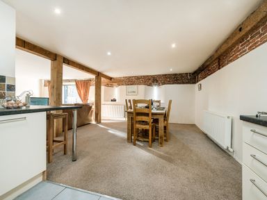 An open plan kitchen and dining area with wooden beams and brick walls at Teal in Wheatacre