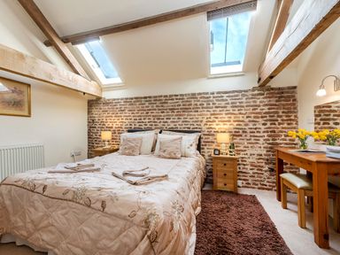 A bedroom with a bed bedside tables a desk and skylights at Teal in Wheatacre