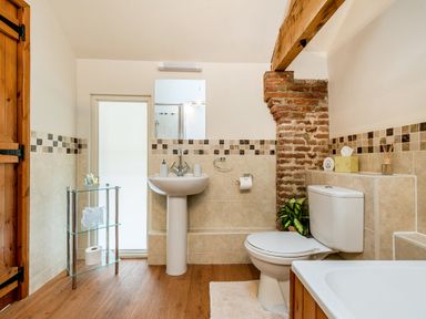 A bathroom with a pedestal sink a toilet a glass shelf and a bathtub at Teal in Wheatacre