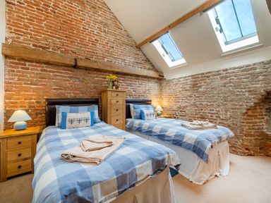 A bedroom with two single beds bedside tables lamps a chest of drawers and skylights at Teal in Wheatacre