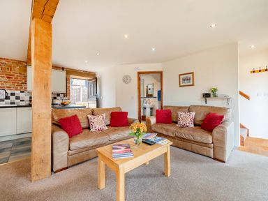 A living room with two brown sofas and a wooden coffee table with books and flowers at Woodcock in Wheatacre