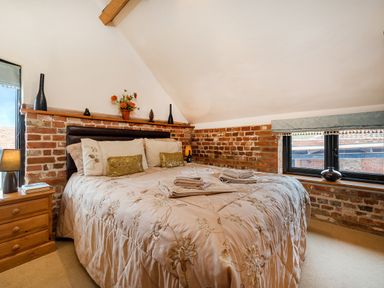 A bedroom with a double bed and floral bedspread beside a window at Woodcock in Wheatacre