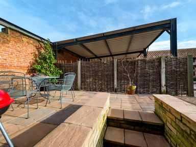 An outdoor patio area with metal chairs and a table next to a brick wall and steps leading to a lower level at Woodcock in Wheatacre