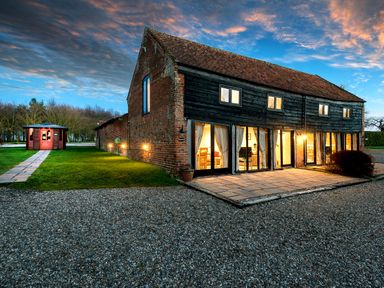 A barn style house with large windows and a small wooden gazebo on a lawn at Snipe in Wheatacre