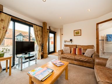 A living room with brown leather sofas a wooden coffee table and large windows at Snipe in Wheatacre