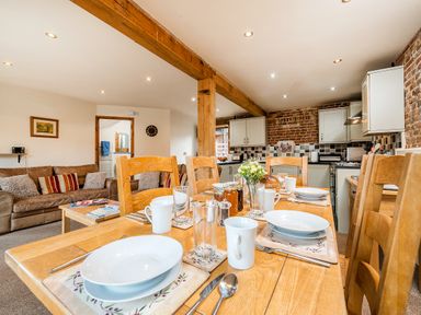 A dining table set with dishes and mugs in an open plan kitchen and living area at Snipe in Wheatacre