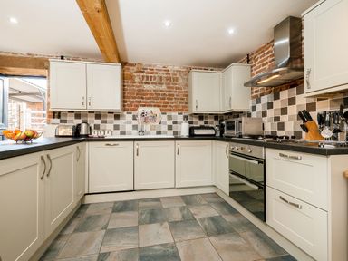 A kitchen with white cabinets tiled backsplash stainless steel appliances and a fruit bowl at Snipe in Wheatacre