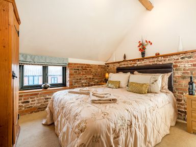 A bedroom with a bed with pillows and towels a wooden wardrobe and a window with a blue curtain at Snipe in Wheatacre