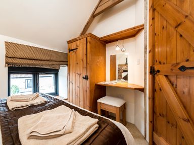 A bedroom with a wooden wardrobe and dressing table next to a window with brown blinds at Snipe in Wheatacre