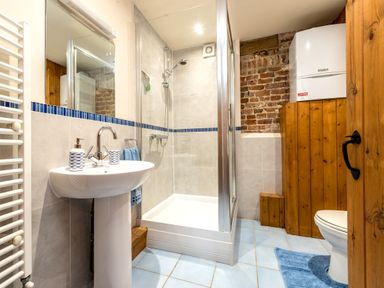 A bathroom with a pedestal sink shower enclosure and toilet with wooden paneling and tiled floor at Snipe in Wheatacre