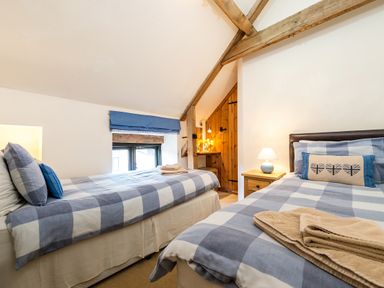 A bedroom with two single beds with checkered bedding and a wooden door at Snipe in Wheatacre
