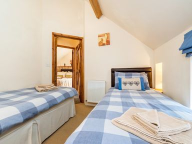 A bedroom with two single beds with checkered bedspreads and a doorway leading to another room at Snipe Wheatacre