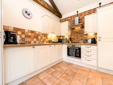 A kitchen with white cabinets a tiled floor and backsplash and appliances at Pheasant in Wheatacre