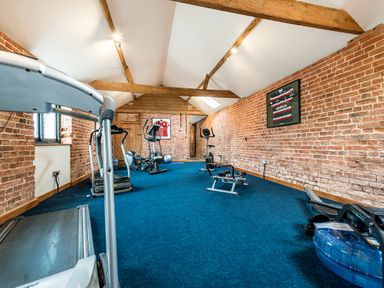 A gym room with exercise equipment and framed shirts on brick walls at Pheasant in Wheatacre