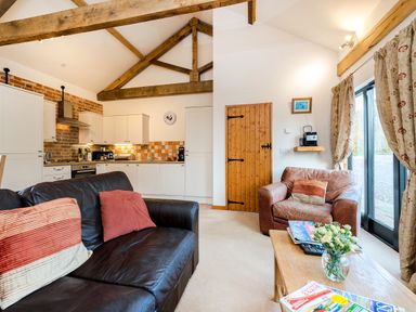 A living room with leather sofas wooden coffee table and an open kitchen with white cabinets at Partridge in Wheatacre