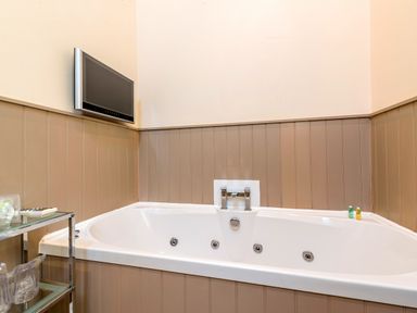 A bathroom corner with a bathtub jets and a wall mounted television at Partridge in Wheatacre