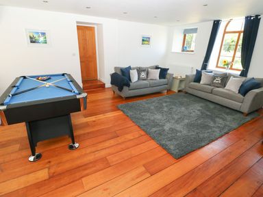 A room with two grey sofas around a grey rug and a blue pool table on a wooden floor at Dalton Cottage in Llansaint