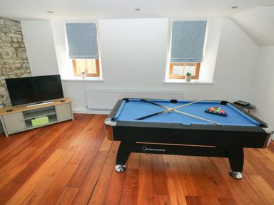 A game room with a pool table and a television on a stand at Dalton Cottage in Llansaint