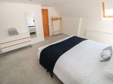 A bedroom with a bed a dresser and a clothes rack at Dalton Cottage in Llansaint