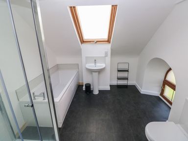 A bathroom with a shower, bathtub, pedestal sink, small window, and toilet at Dalton Cottage in Llansaint