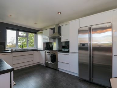 A kitchen with white cabinets stainless steel appliances and a window showing trees at Te Papa in North Petherton