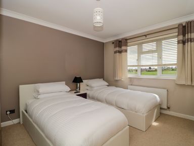 A bedroom with two single beds a nightstand and a window with curtains at Te Papa in North Petherton