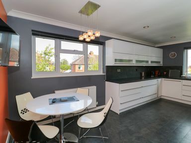 A kitchen with white cabinets a round dining table and four chairs at Te Papa in North Petherton