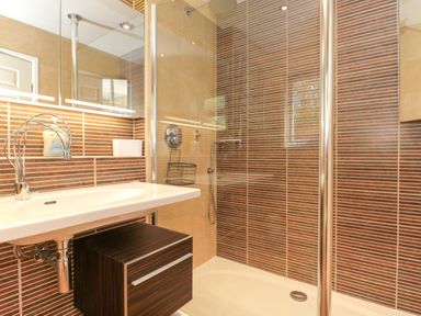 A bathroom with a sink and a shower with striped brown tiles at Te Papa in North Petherton