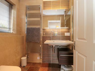 A bathroom with a wall-mounted sink mirror cabinet towel rack and window at Te Papa in North Petherton