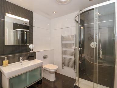 A bathroom with a sink cabinet mirror toilet towel rack and a glass shower enclosure at Te Papa in North Petherton
