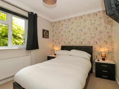 A bedroom with a bed bedside tables lamps and a window with curtains at Te Papa in North Petherton