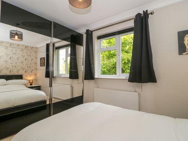 A bedroom with a bed a window with closed curtains and a mirrored wardrobe at Te Papa in North Petherton