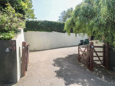 A driveway with wooden gates and green bins behind a white wall at Te Papa in North Petherton