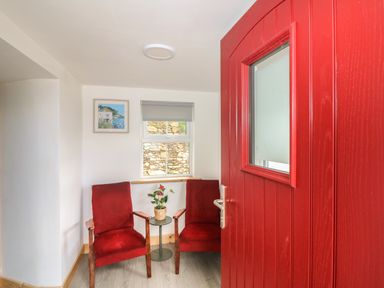 A small seating area with two red chairs and a table with a plant at Curragh Cottage in Rathimney near New Ross County Wexford