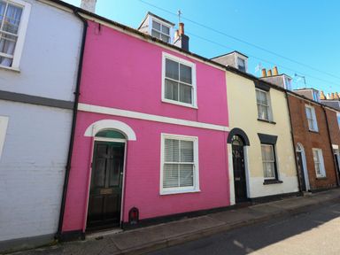 A row of brick terraced houses with colorful facades and black doors on a street at Georgian Hideaway in Weymouth
