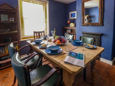 A dining room with a wooden table set for six with blue plates bowls and glasses at Georgian Hideaway in Weymouth