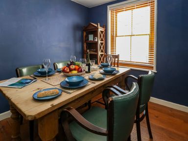 A dining room with a wooden table set with plates bowls glasses fruit and bread and green chairs at Georgian Hideaway in Weymouth